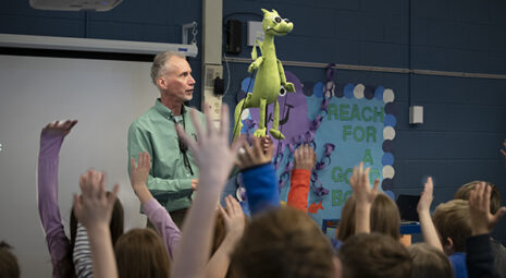 Author David LaRochelle presenting before students with a dragon puppet