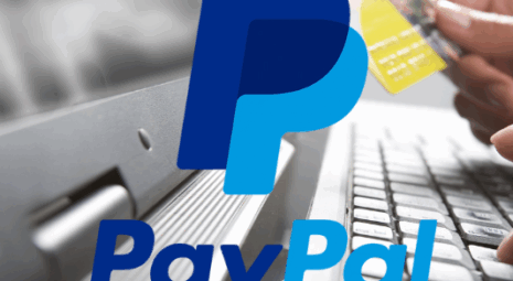 laptop with person holding credit card and paypal logo