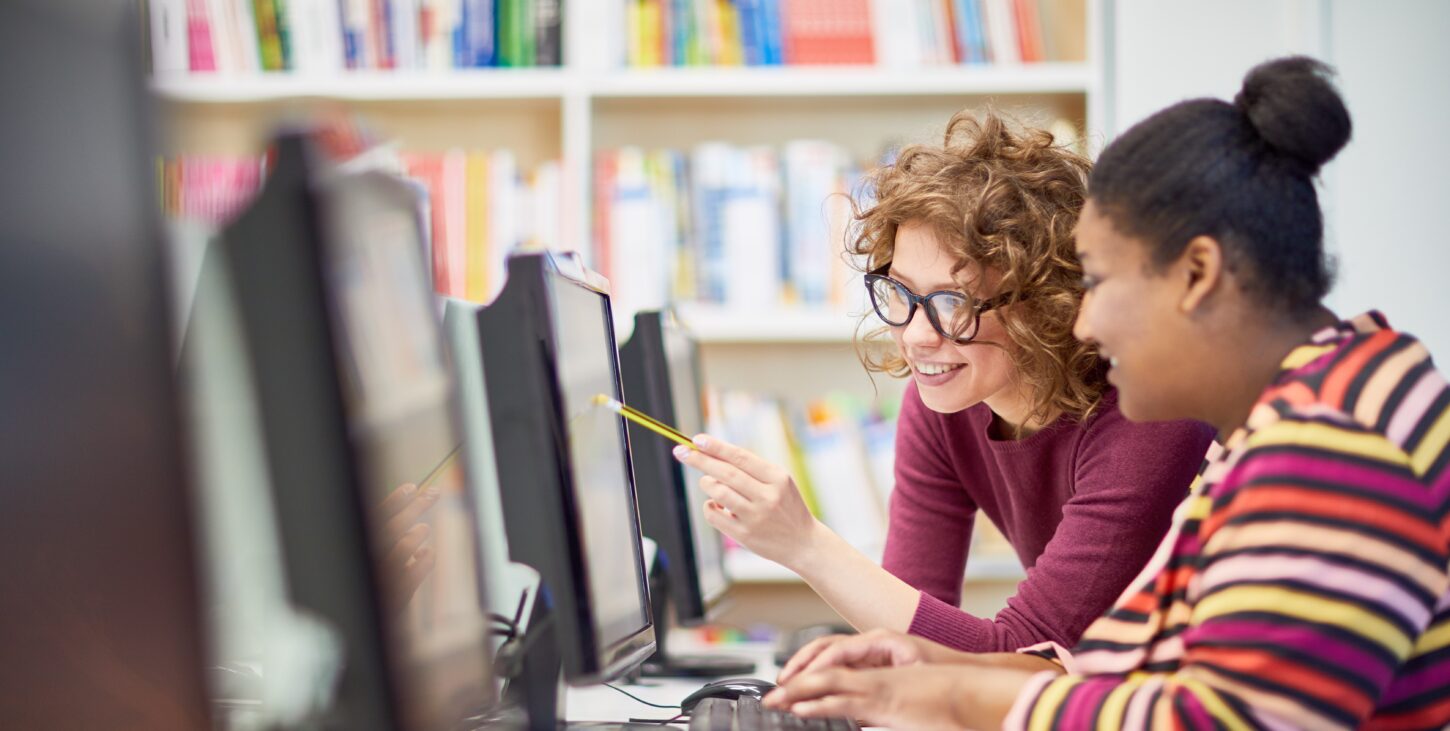 image of a woman helping another woman on a computer