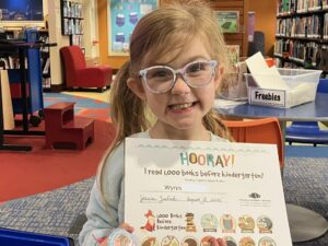 Girl with glasses smiling and holding certificate and button
