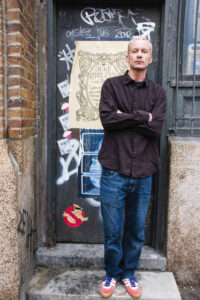 Chris Collingwood leaning against a wall with graffiti in the background
